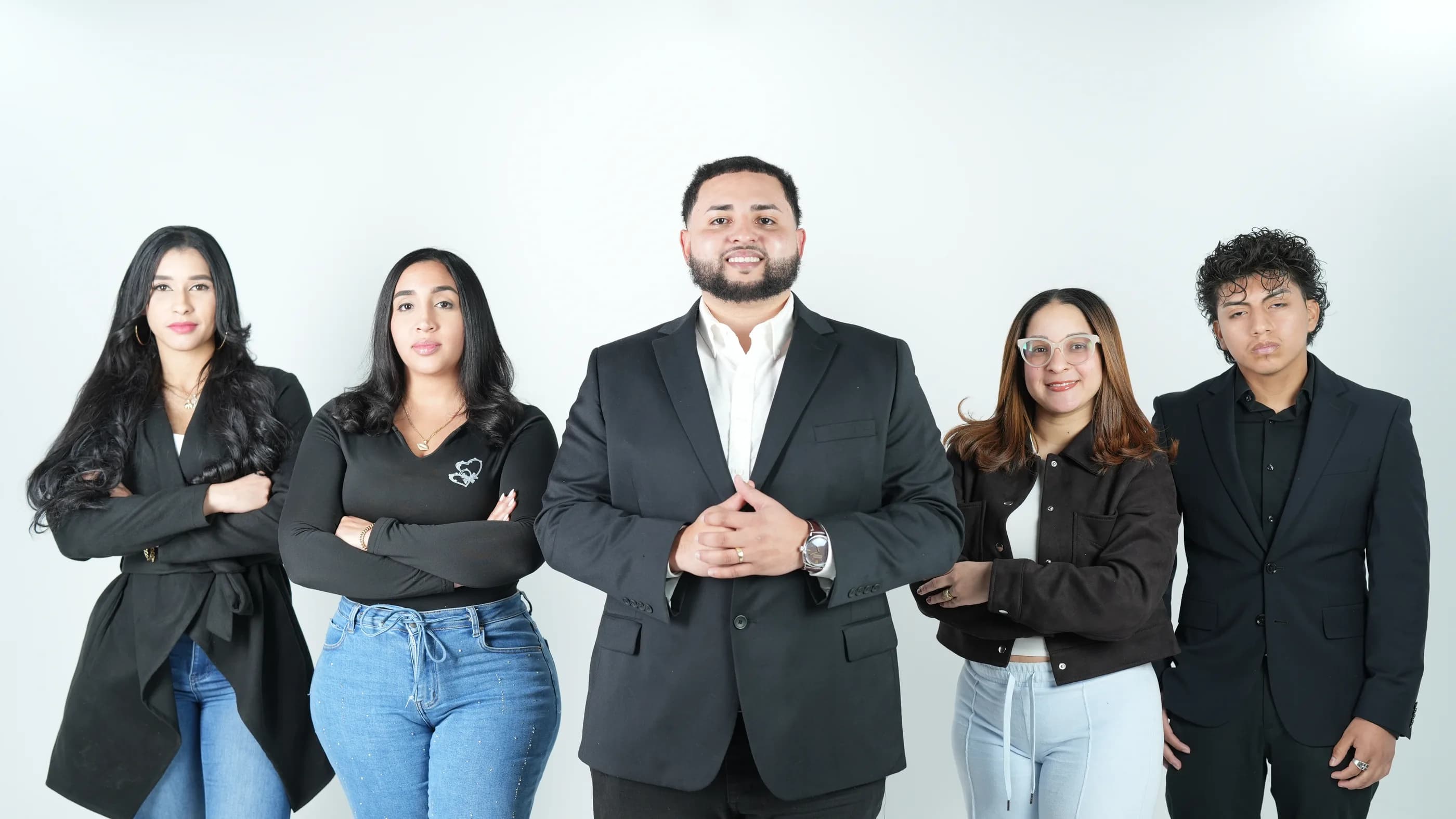 El equipo: cinco personas de pie en un estudio de fondo blanco, Enrryko Placencia en el centro de traje negro